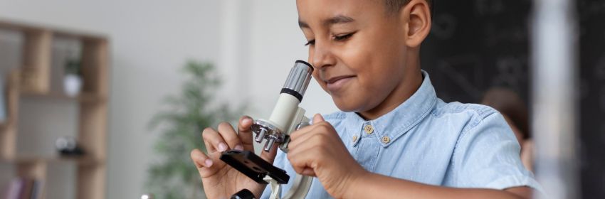 criança-negra-com-lupa-analisando-lapis-e-brinquedos-encima-da-mesa